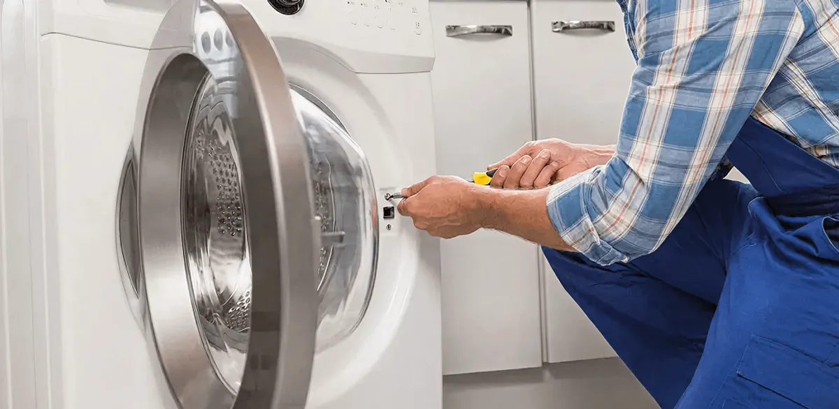 Handyman repairing a clothes dryer and checking electrical connections in Riverside, CA