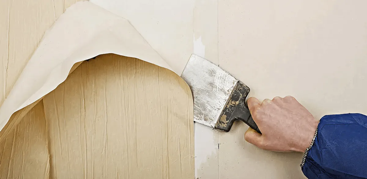 Handyman removing wallpaper with a scraper for wall preparation in Riverside, CA